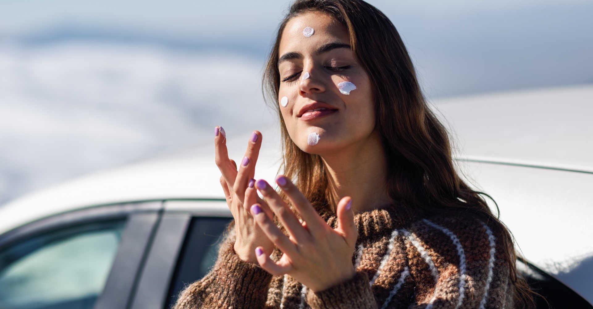 Modelo branca passando protetor solar no rosto